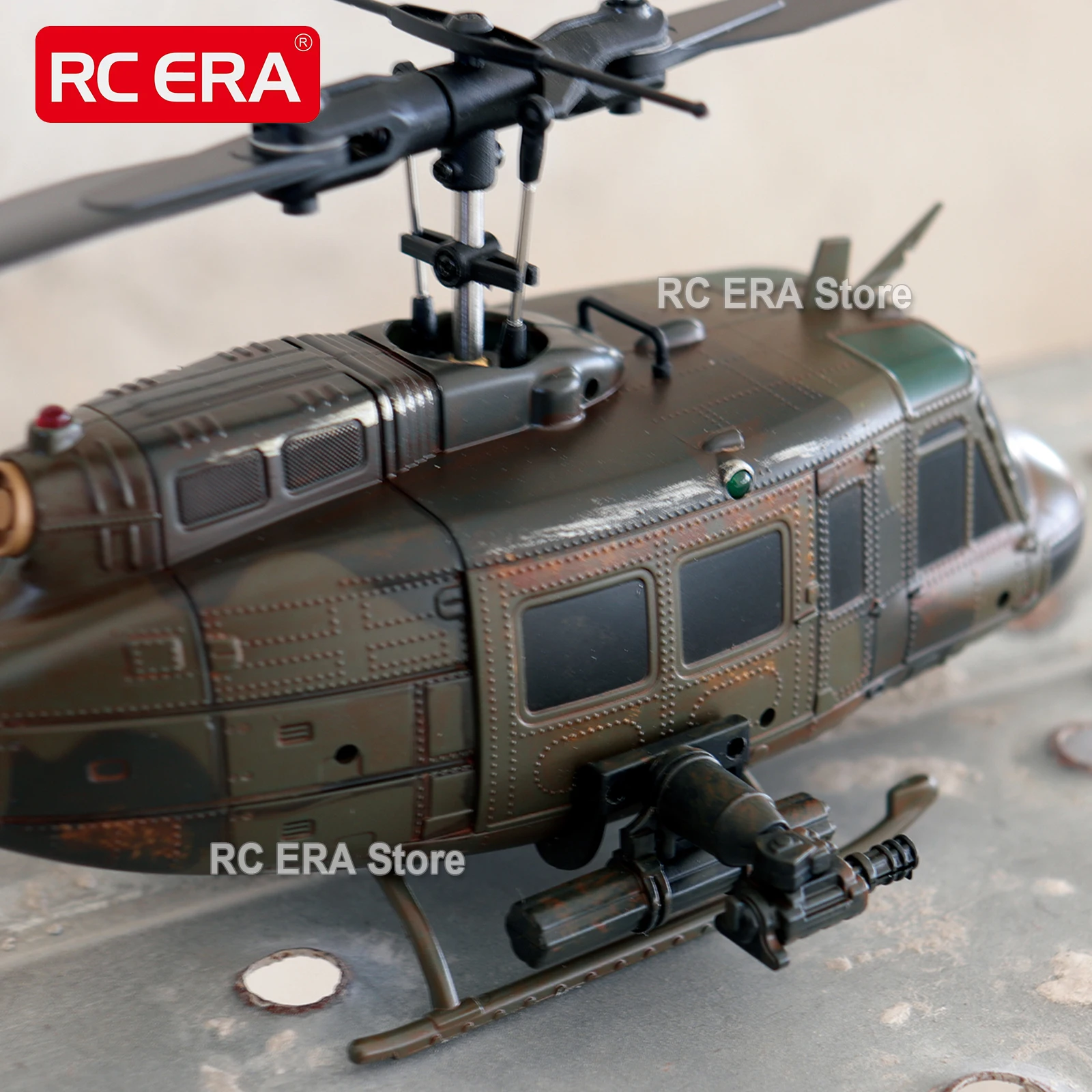 Hélicoptère RC C032 UH1 Huey camouflage vieilli posé sur une piste, vue latérale avec train d'atterrissage.