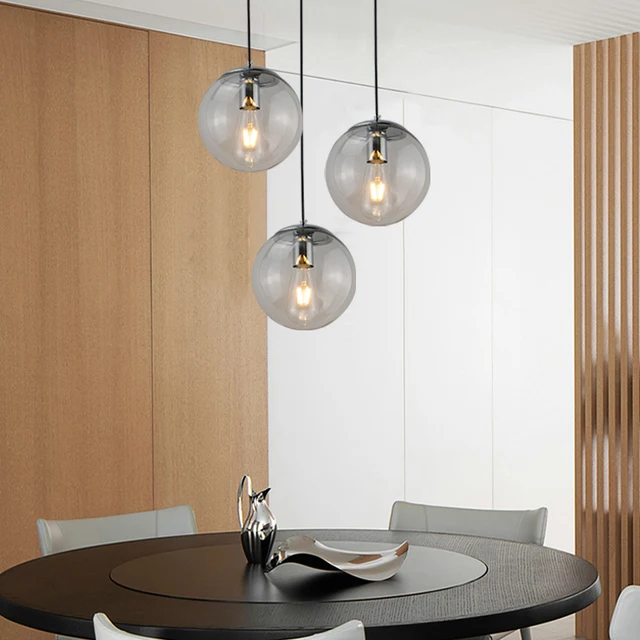 Suspension globe en verre design moderne de couleur noire présentée 3 fois au-dessus d'une table à manger