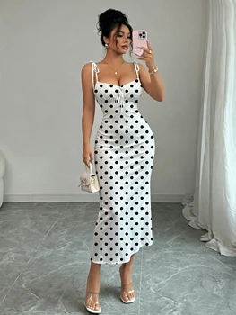 Robe sirène noire à pois sur fond blanc, avec double nœud papillon aux épaules et fronces sur la poitrine pour une mise en valeur de la taille, coupe ajustée, moulante aux hanches, longueur mi-longue