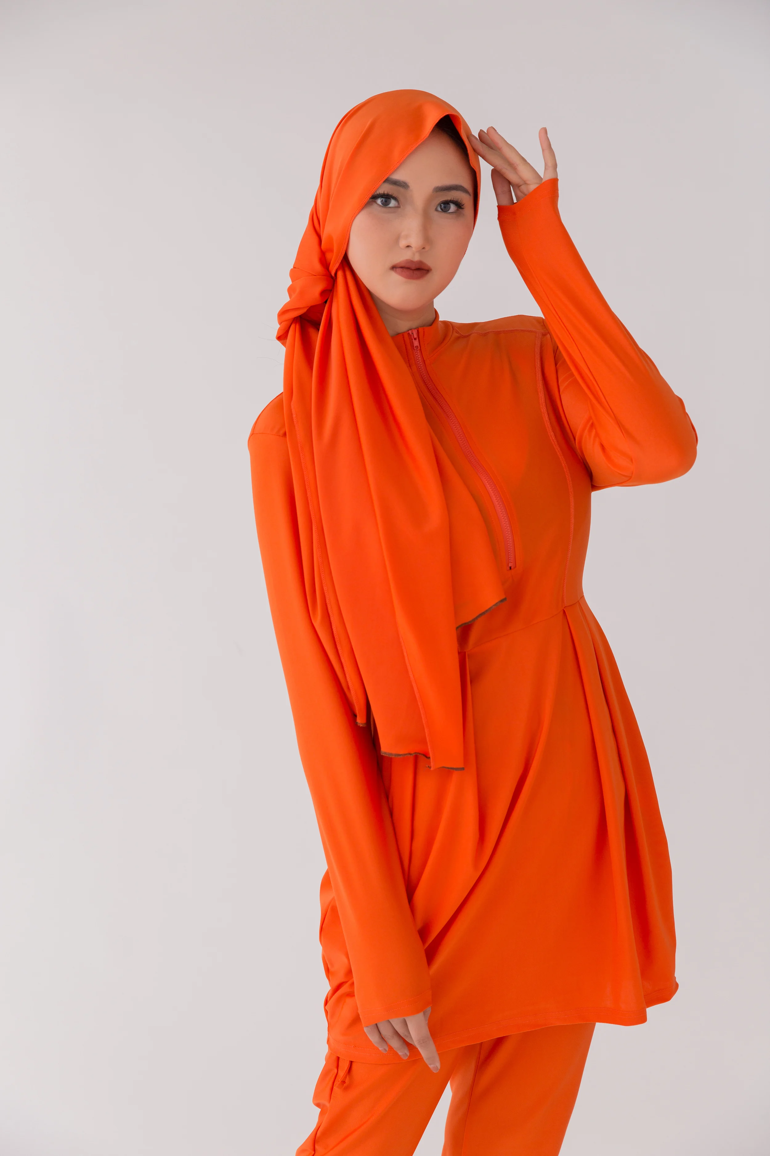 Muslim woman relaxing on the sand wearing purple Islamic swimming suit