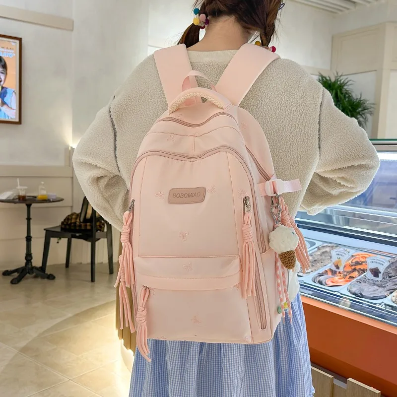 Sac à dos TRAVEASY 2026 Nouveau Motif Nœud Mignon Polyvalent en Nylon avec Pendentif Pompon Protection Dorsale pour Étudiants