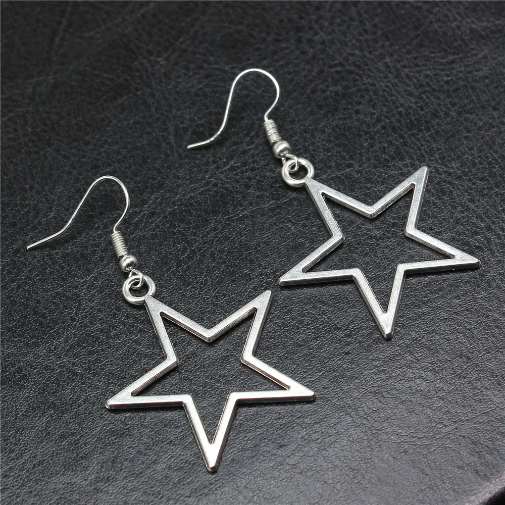 A pair of Hollow Star Pendant Drop Earrings for Women on a black surface.