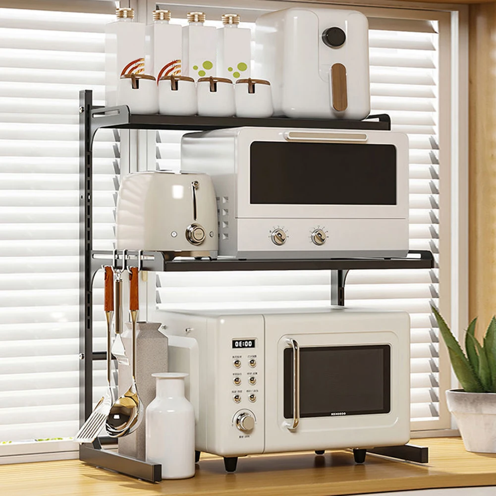 Expandable 2-tier microwave shelf in black, holding a microwave and other kitchen items on a countertop.