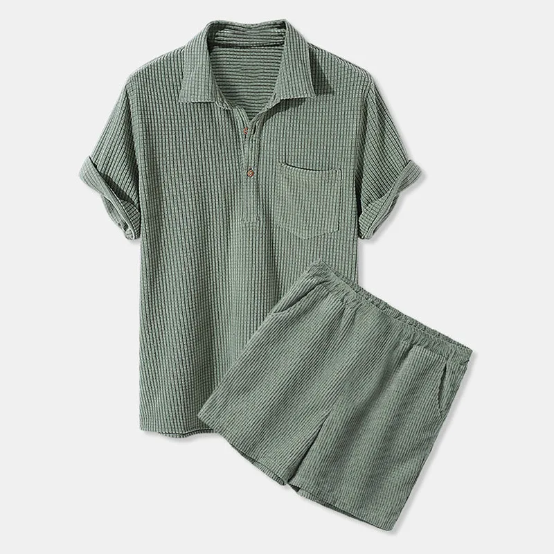Man wearing a solid-color corduroy lapel shirt and matching shorts, standing confidently in a sunlit urban setting green