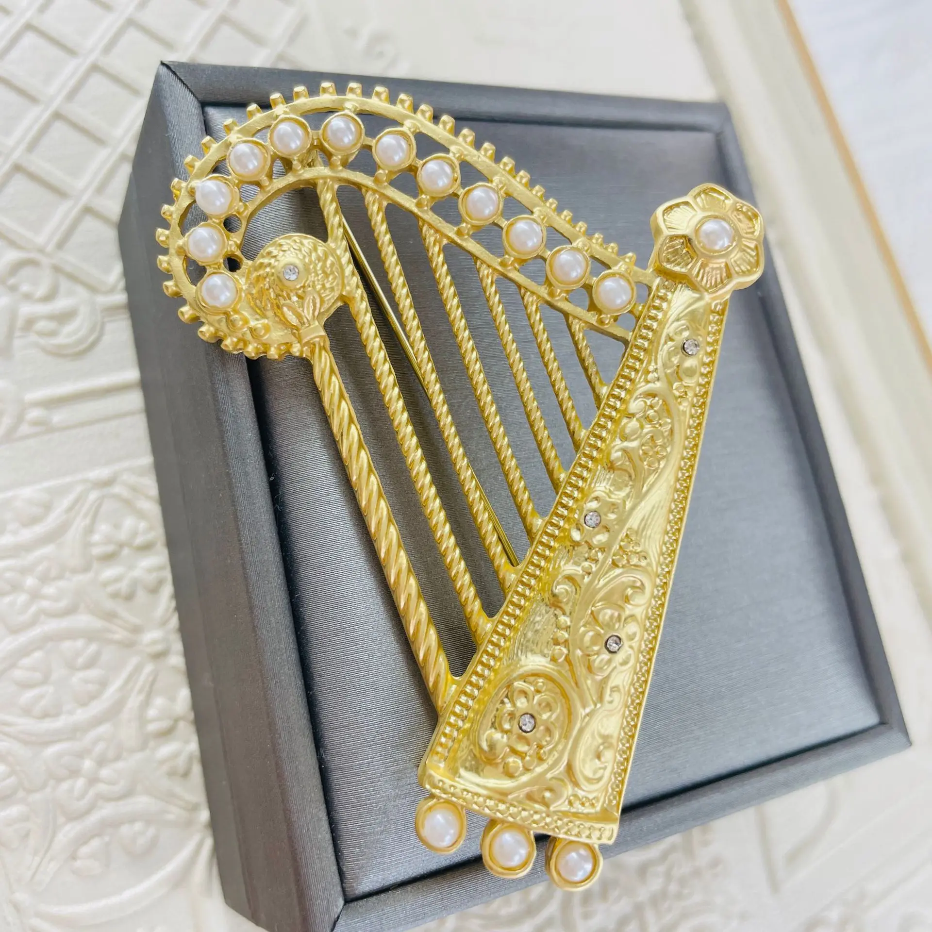 

French style pearl studded rhinestone three-dimensional harp hollow out brooch is popular in Europe and America. Pin accessories