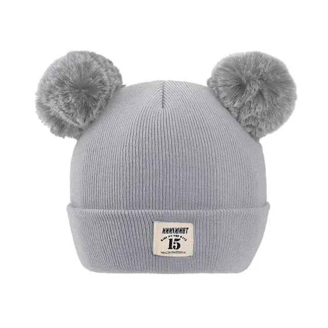 Gray knit beanie with fluffy pom-poms, perfect for cold weather, stylish, and cozy. Ideal for kids and adults to stay warm and fashionable during winter sports, outdoor activities, or casual outings.