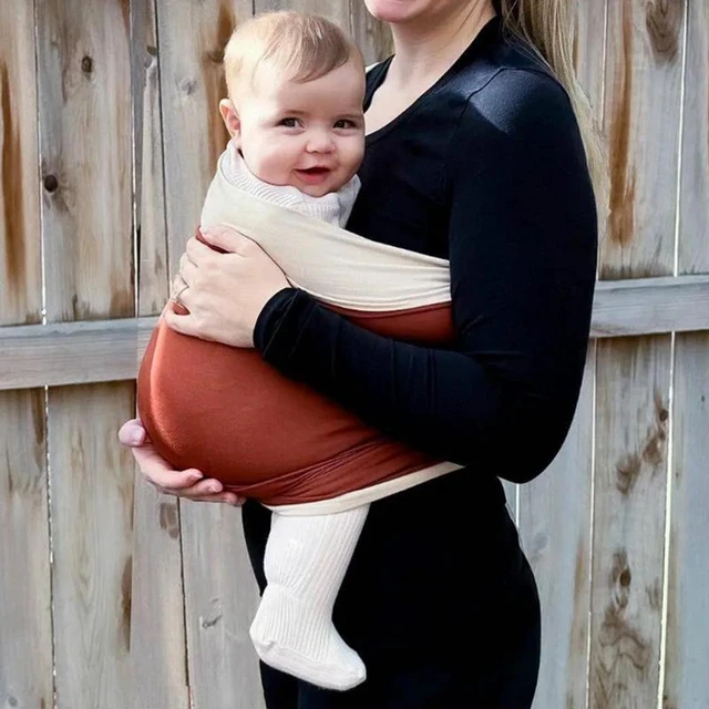 Instructora de porteo con un bebé recién nacido envuelto en un cabestrillo  muestra sus manos libres.