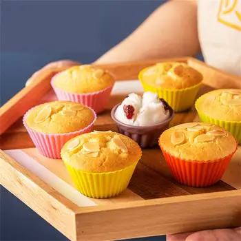 Colorful muffins in pink, yellow, and orange baking cups served with a side of whipped cream and berry topping.