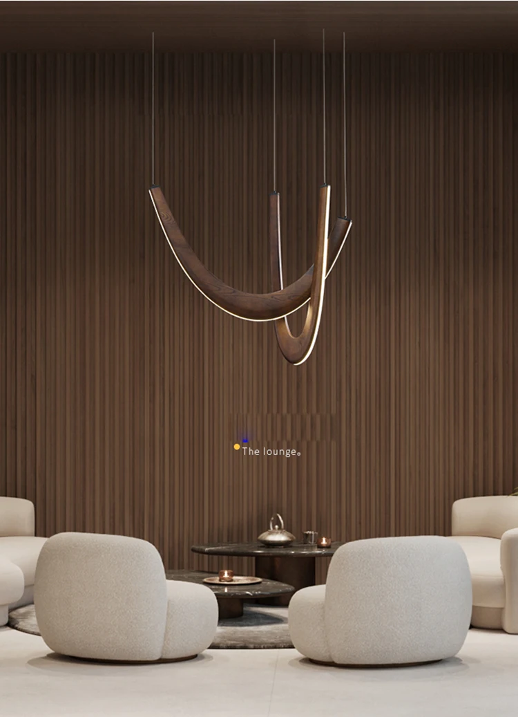 Modern lounge area featuring four rounded white chairs, a circular wooden coffee table, and the Double Curve Wood Pendant Light against a wood-paneled wall.