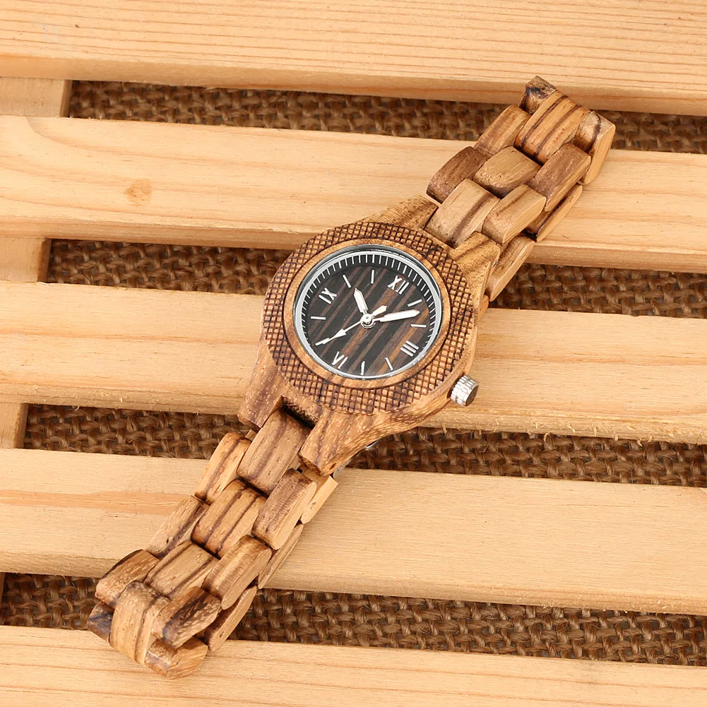 Elegantne puidust käekell naistele, millel on naturaalne puitmaterjal, pruun toon ja must sihverplaat. Kella taustal paistab hele puitpind, mis rõhutab kella looduslikku esteetikat.