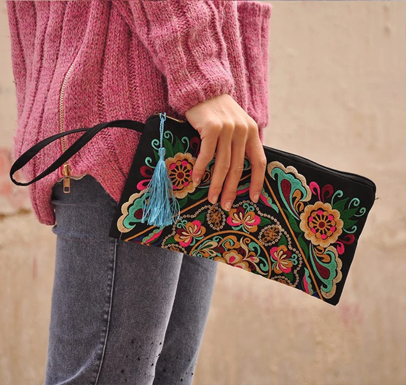 A retro woman clutching an Ethnic Retro Flower Clutch Bag with a tassel.