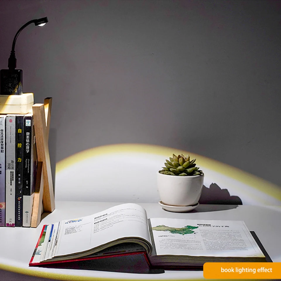 an open book sitting on top of a table next to a sunset lamp| Brookline Shop