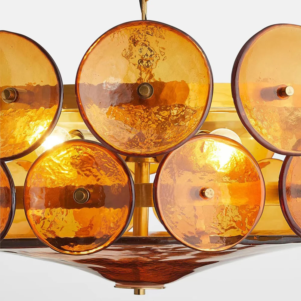 Close-up of the Italian Retro Pendant Light, a Mid-Century Modern chandelier with textured amber glass discs on a gold metal frame, beautifully illuminated.