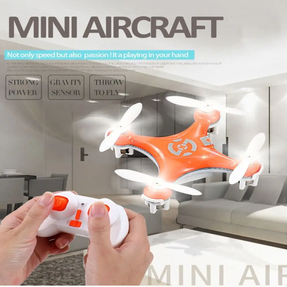Mini drone jouet enfant orange posé sur une table, avec câble USB pour recharge, idéal pour débuter.