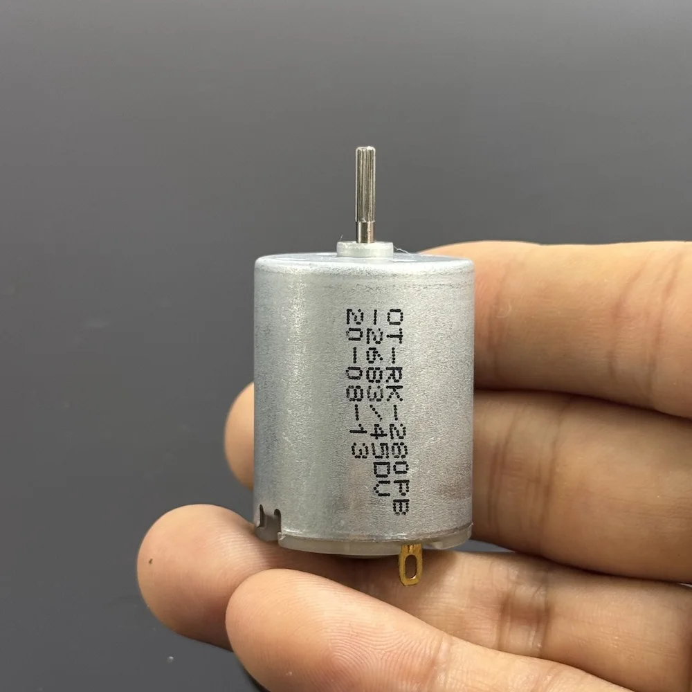 Moteur miniature 280 à balais charbon posé sur une surface blanche, prêt à l'emploi