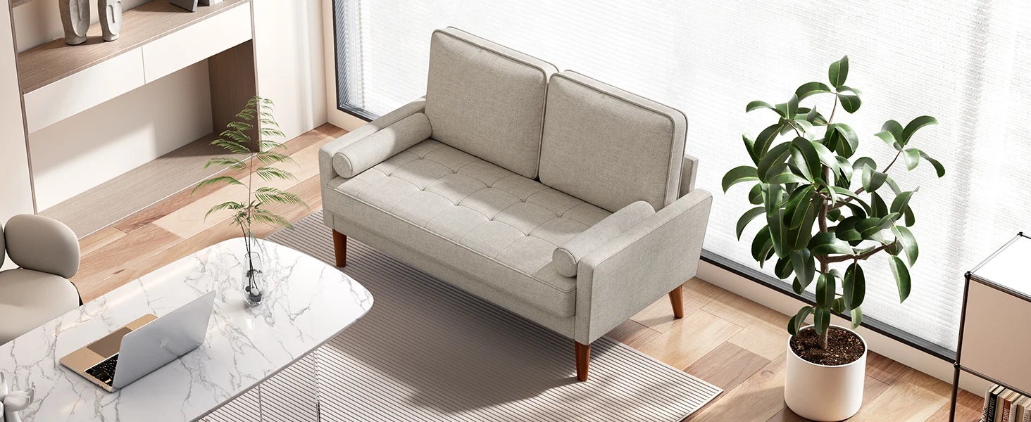 Modern light gray two-seater sofa with tapered wooden legs in a minimalist living room setting with natural lighting and houseplant.