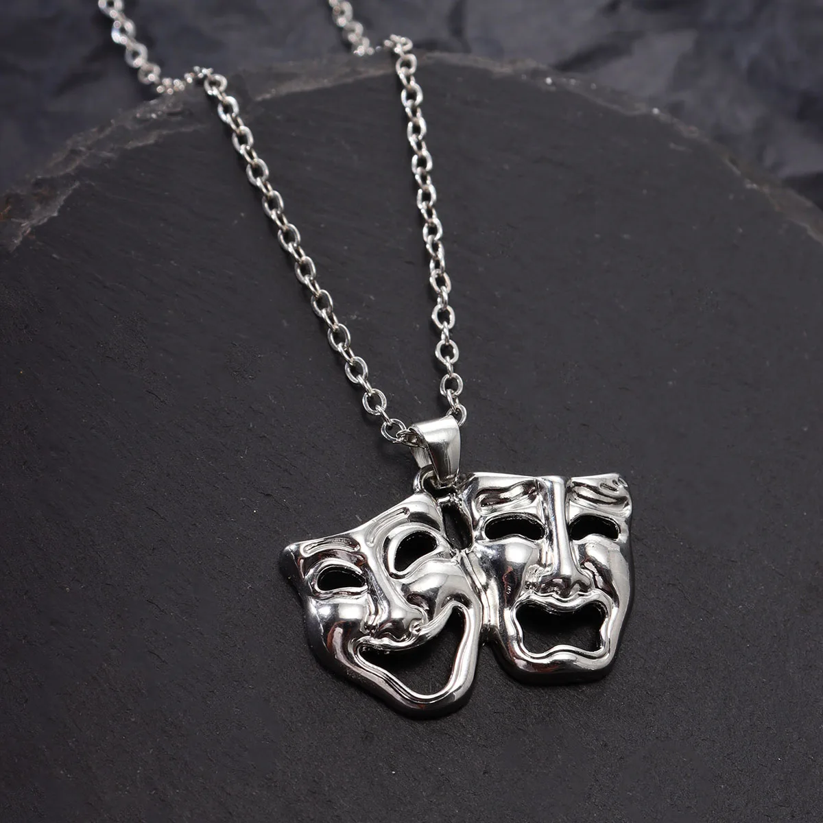 Vue rapprochée du collier pendentif masque de théâtre argenté, détails sculptés et fermoir robuste.