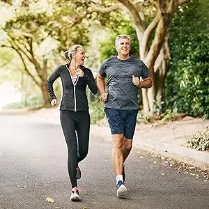 middle aged couple happily running in park