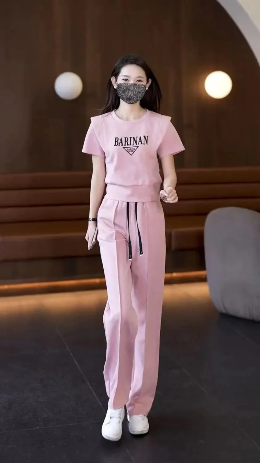 Women's summer fashion sweatsuit in vibrant apricot color featuring short sleeves and elegant trousers.