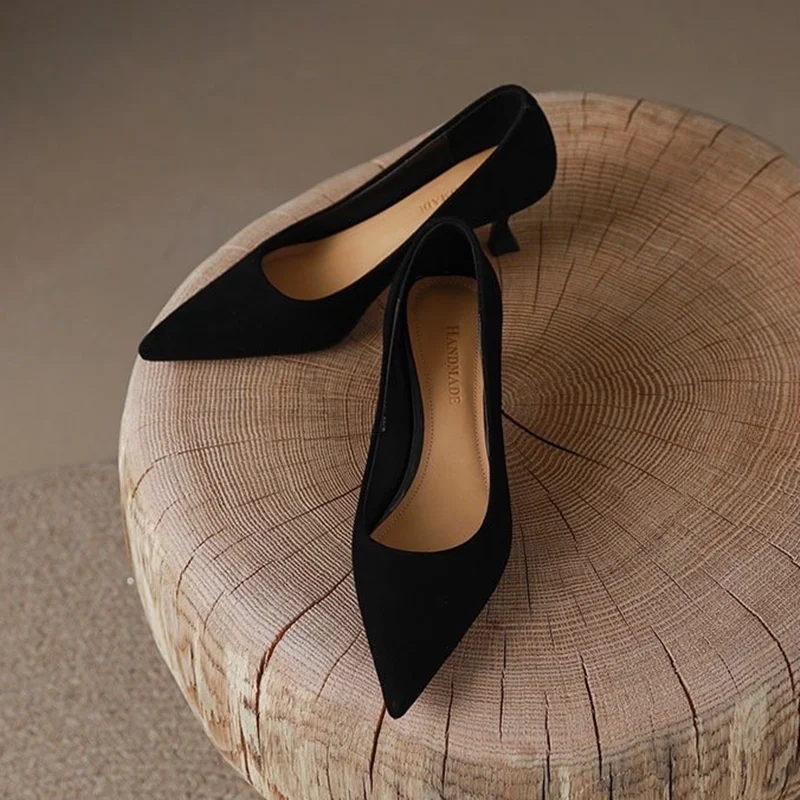 Black Pointed Toe Kitten Heel Pumps Black pointed toe kitten heel pumps displayed on a wooden stool