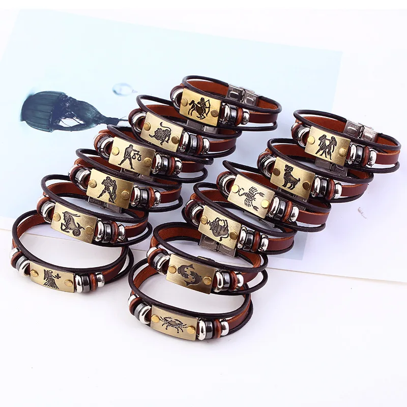 Set of brown leather bracelets with metal zodiac charms on a white background