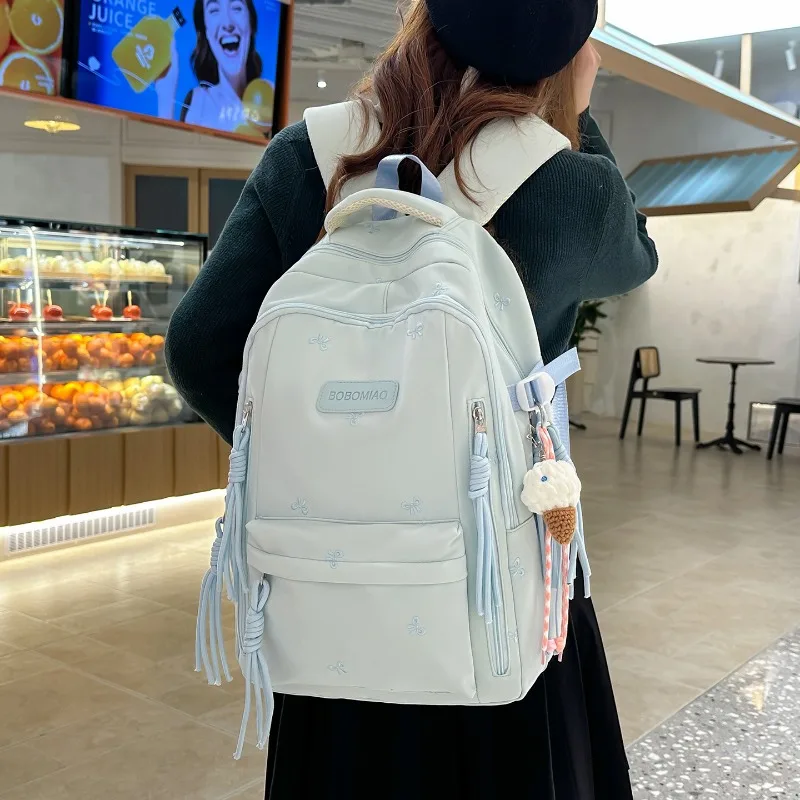 Sac à dos TRAVEASY 2026 Nouveau Motif Nœud Mignon Polyvalent en Nylon avec Pendentif Pompon Protection Dorsale pour Étudiants