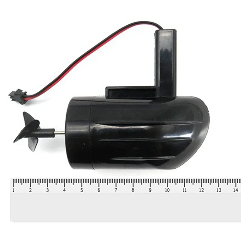 Moteur de bateau télécommandé 13cm posé sur fond blanc, avec hélice et support de fixation visibles.