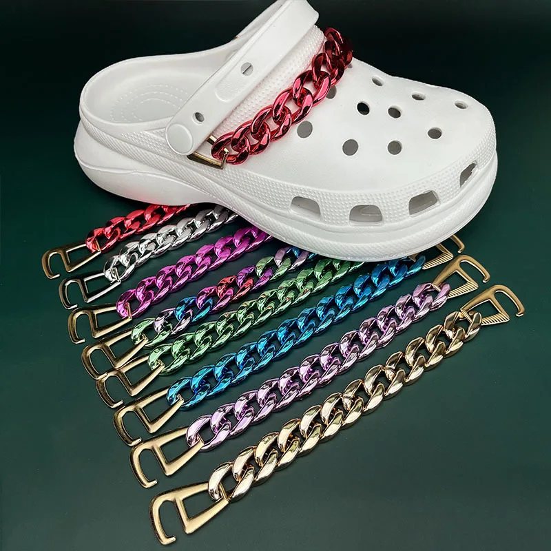 White clog shoe with colorful chain straps on a green background