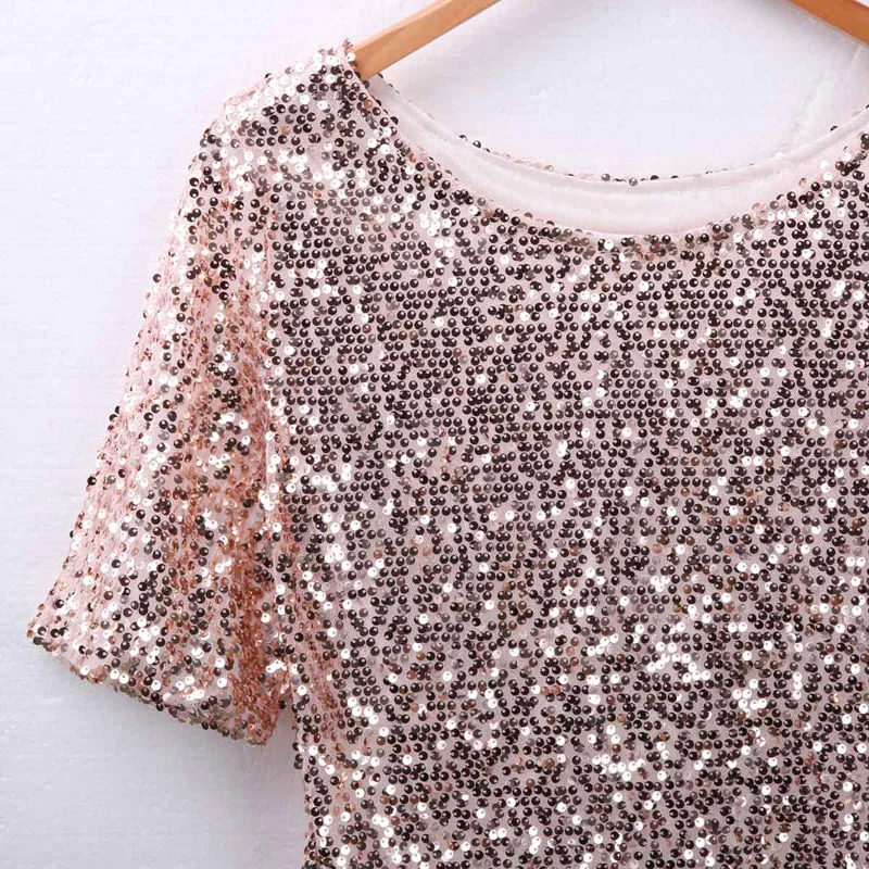Woman wearing sloping shoulder sequin T-shirt in a casual streetwear setting with soft lighting 02