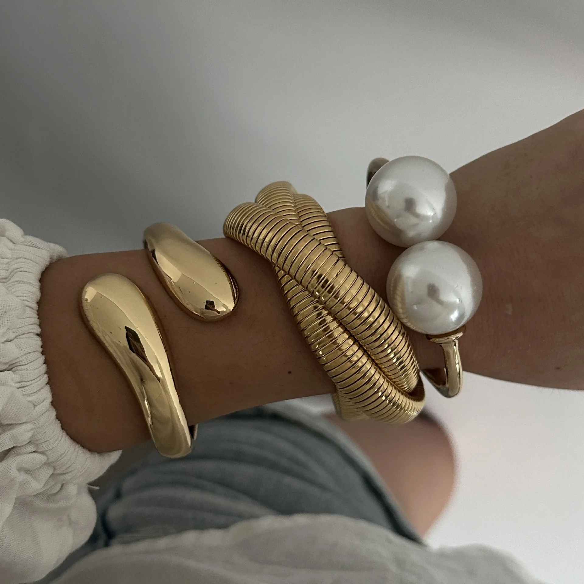 Gold-tone cuff bracelet with pearl ends for women – wide statement bangle with modern fashion appeal.