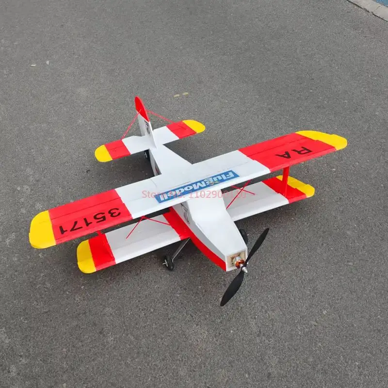 Avion RC biplan à décollage et atterrissage rapides en vol au-dessus d'un champ, ailes en polypropylène de 1000mm d'envergure.