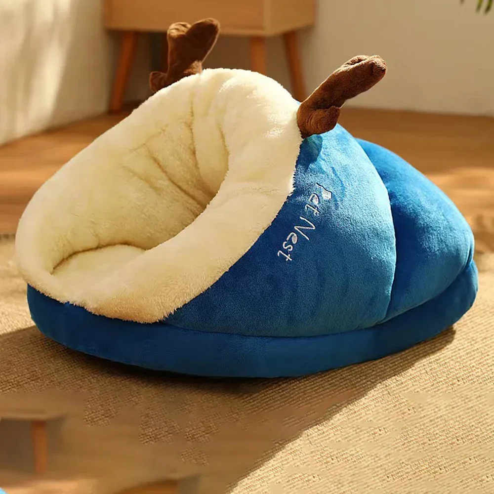 A deep sea blue, hooded Warm Pet Bed featuring a plush cream-colored fleece interior and decorative brown reindeer antlers on top.