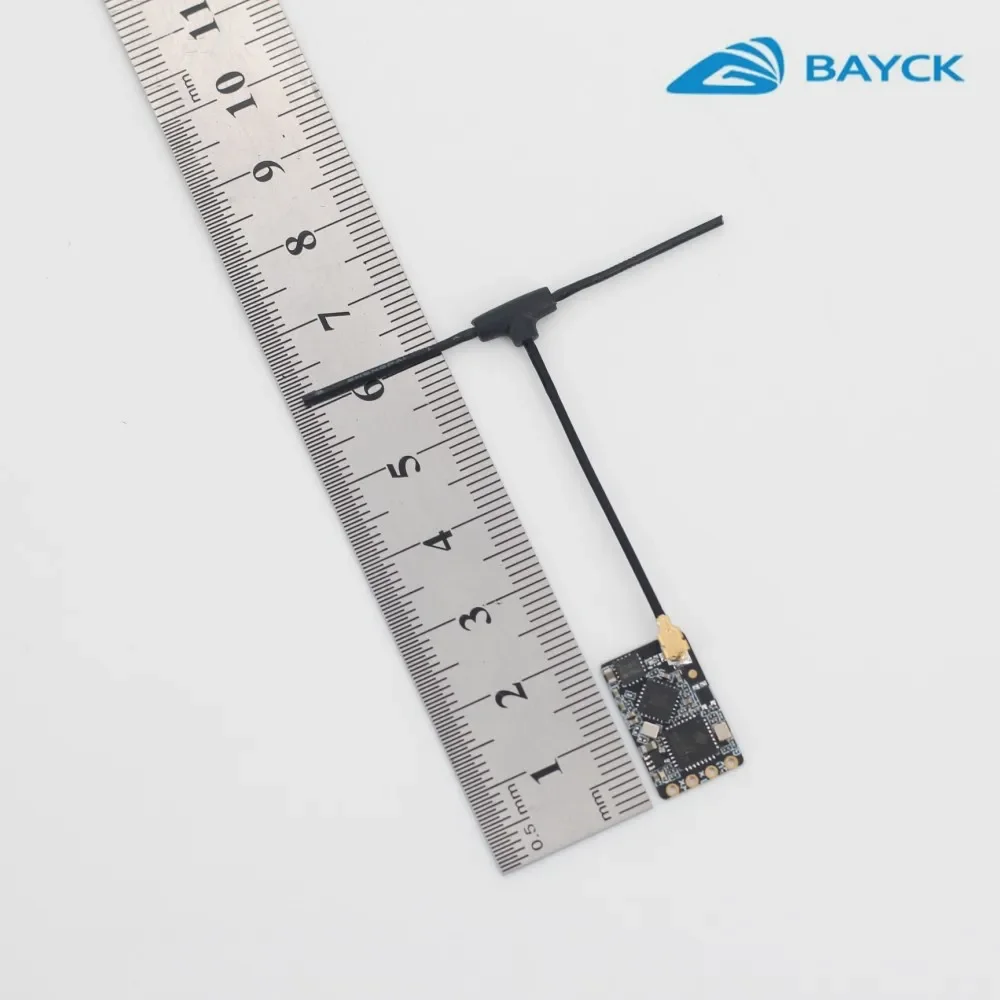 Récepteur BAYCK ELRS 2.4G NANO 100mW posé sur une surface, comparaison de taille avec une pièce de monnaie.