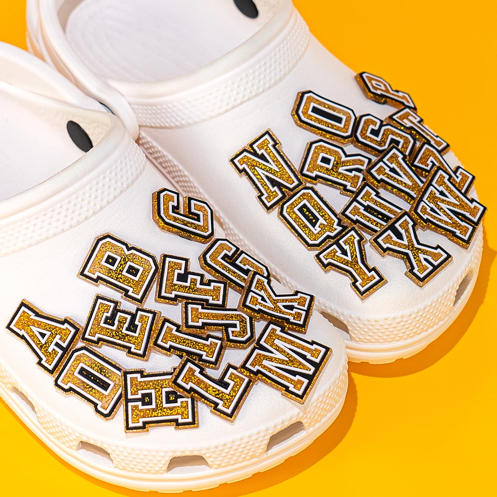 Gold glitter A–Z letter shoe charms set on white clogs – perfect for personalization and DIY flair