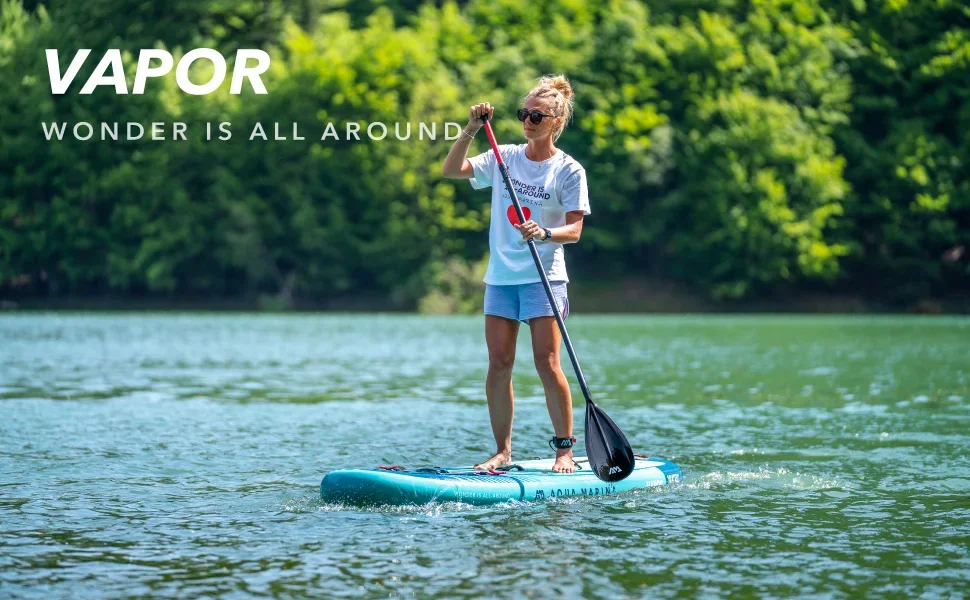Woman holding a paddle while on the VAPOR SUP in the water. 