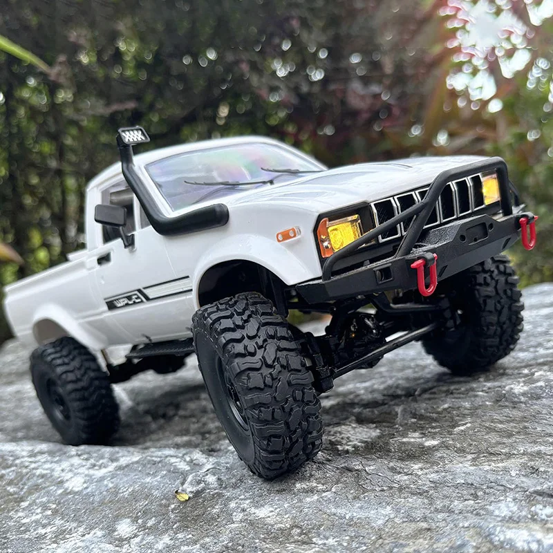 Voiture RC 1:16 4WD C24-1 en pleine course sur un sol rocailleux, roues crantées en mouvement.