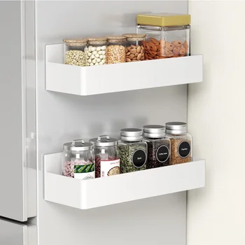 A 2-tier magnetic fridge organizer in black, attached to the side of a stainless steel refrigerator and holding spices and a paper towel roll.