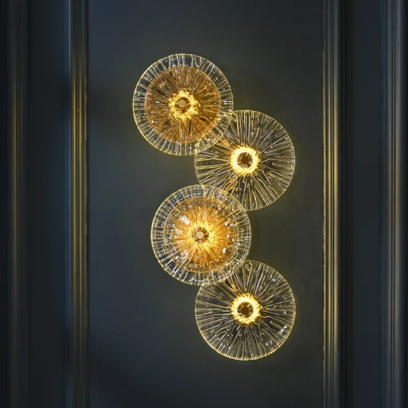 Four Amber Deco Wall Sconce lights with golden glass are mounted vertically on a dark wall, casting a warm, ambient glow and gentle, radiating lines with their nature-inspired design.