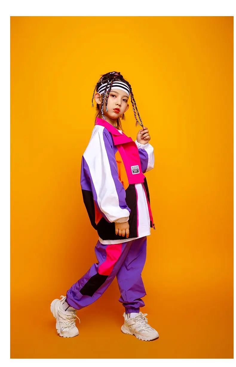 Child wearing patchwork jacket and joggers in hip hop street dance pose 6547