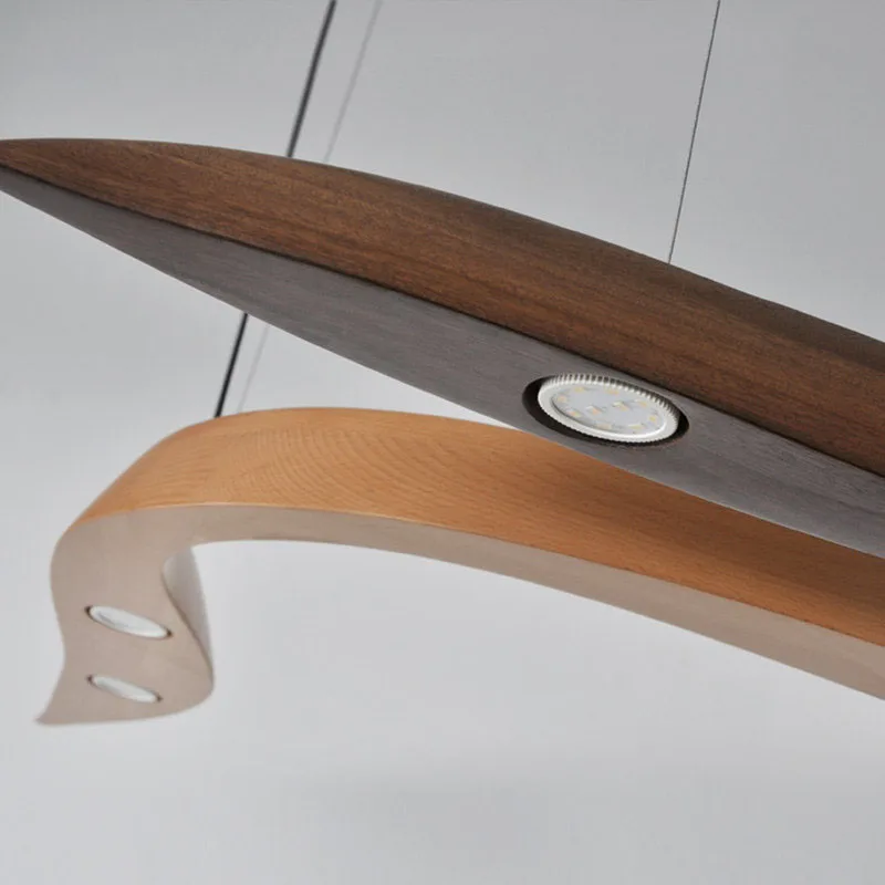 Close-up of two Spiral Wood Pendant Lights, each modern and curved, suspended by wires with built-in circular LED lights.
