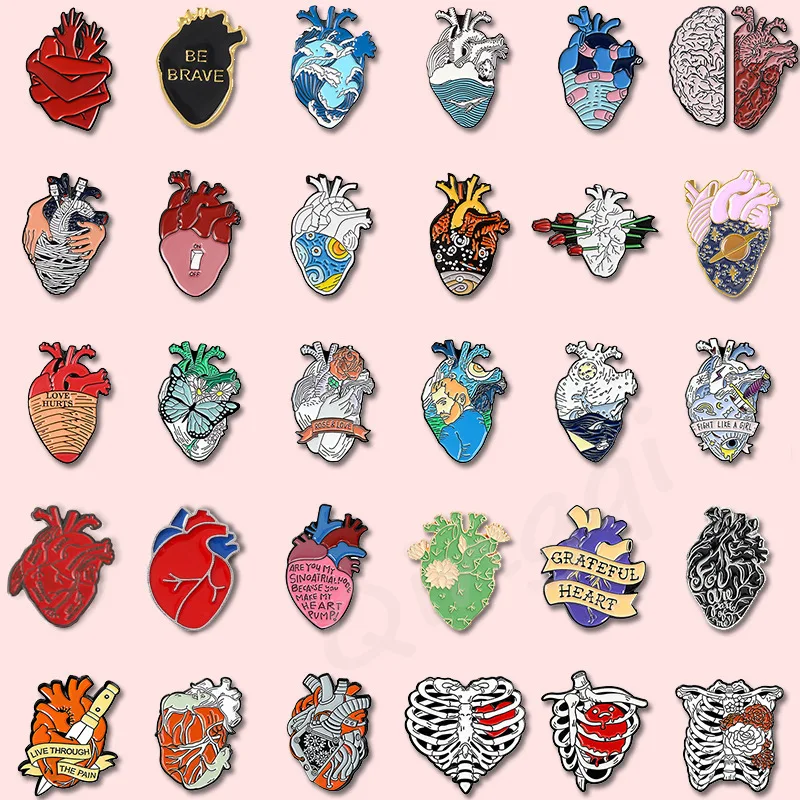 Colorful enamel pins in heart, skull, and anatomical shapes arranged on a pink background – 10–20pcs pack.