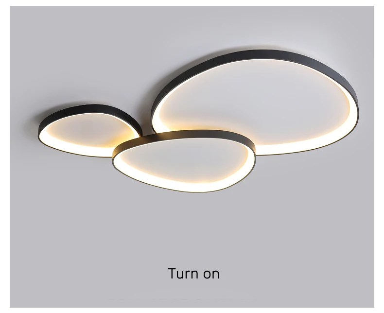 The Nordic Minimalist Ceiling Light features three interconnected oval shapes that emit a soft glow. It offers dimmable brightness for versatile ambiance settings, with "Turn on" text below the fixture.