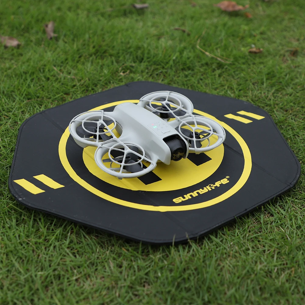 Drone DJI Mini4Pro en vol au-dessus d'un tapis d'atterrissage pliable déplié au sol