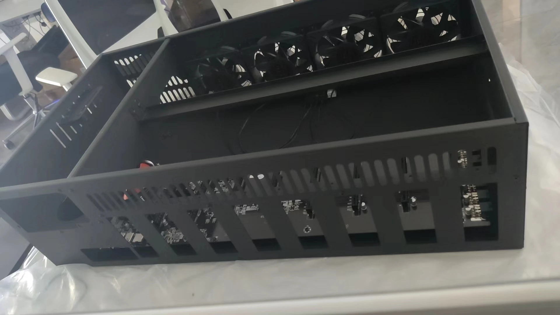 A set of eight PCI card slots in a miner's chassis. The mainboard model is ETH B85 V2.11. There is one fan on the mainboard