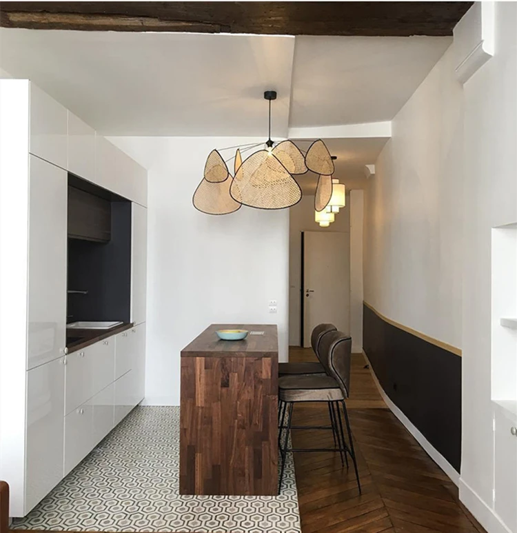 A kitchen with a handwoven wicker chandelier and matte black metal accents, featuring wooden floors and a wooden bar.