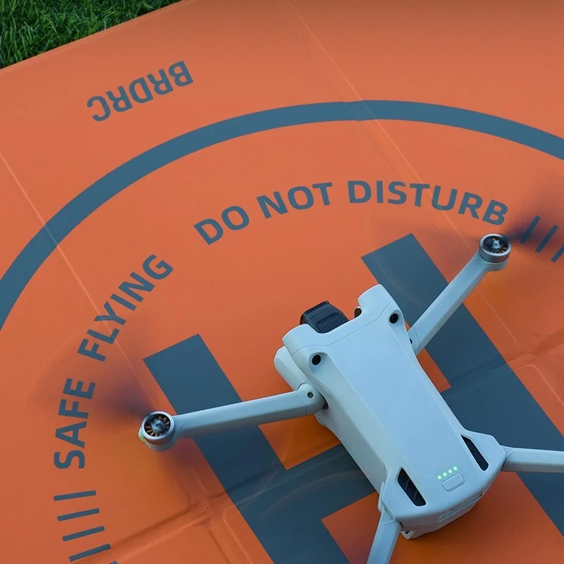 Drone DJI posé sur le tapis de protection d'atterrissage pour drone, avec les patins bien centrés sur la surface antidérapante.