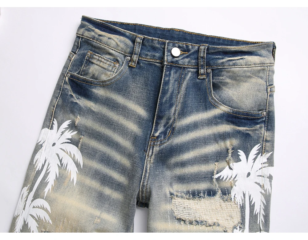 Close-up of front pockets, belt loops, button-zip closure, and washed denim coconut palm print.
