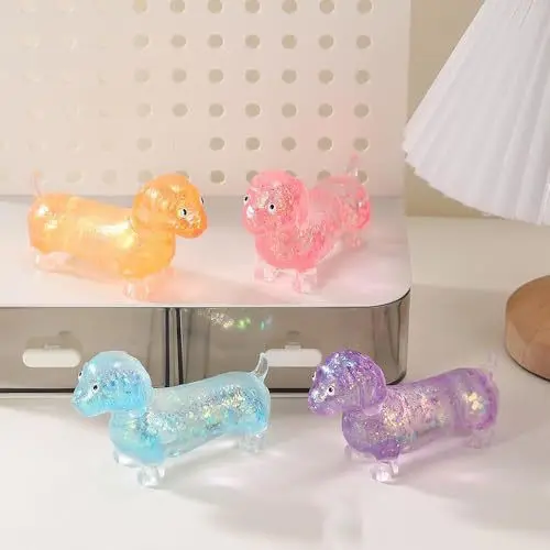 A collection of transparent glitter dachshund squishy stress toys in pink, purple, orange, and blue colors showing extreme stretching and squeezing actions on a desk