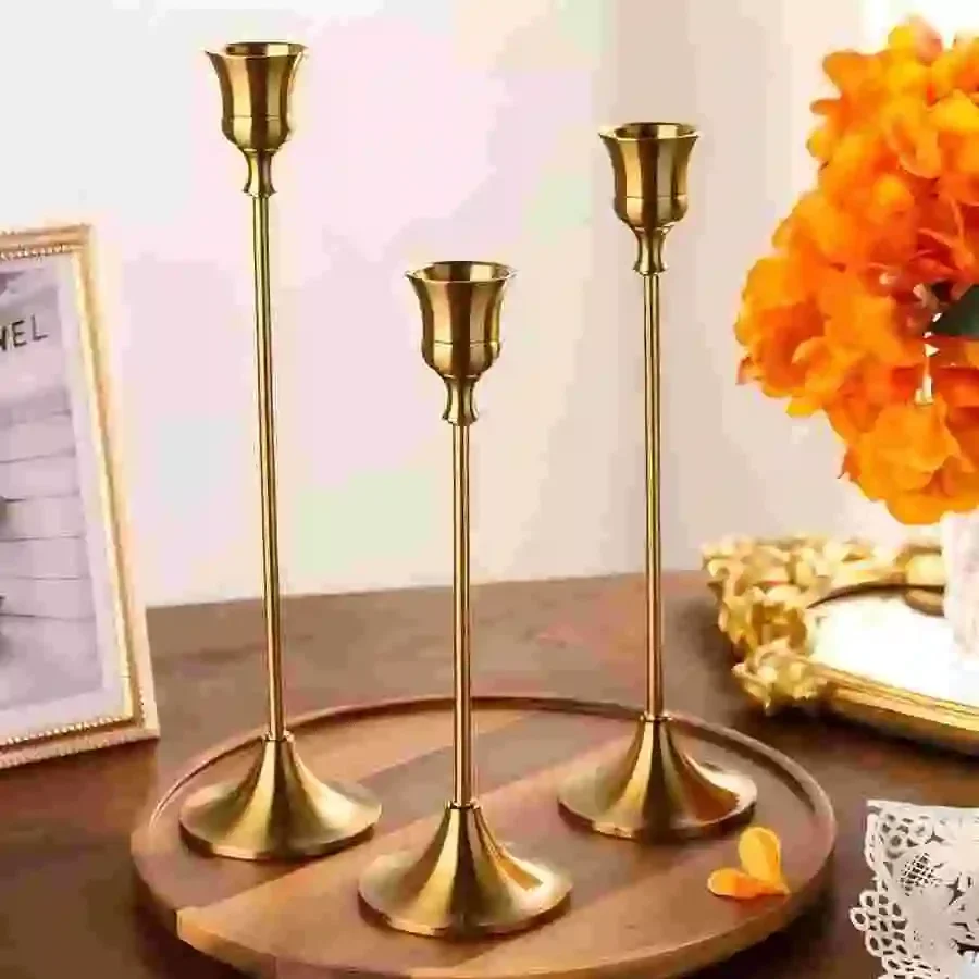 שלושה פמוטים מוזהבים ניצבים על מגש עץ עגול במרכז שולחן