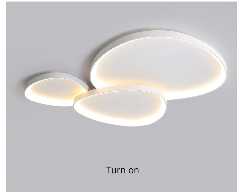 The Nordic Minimalist Ceiling Light features a modern design with three overlapping white ovals, offering a soft glow. It includes dimmable brightness and color temperature control for customizable ambiance, and a "Turn on" label below.